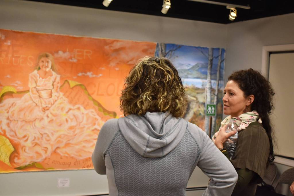 Charlotte Coots speaks in front of She Rides Her Story Like a Cloud, one of her pieces, at the Mural 2022 opening reception at Kenai Art Center in Kenai, Alaska, on Thursday, Nov. 10, 2022. (Jake Dye/Peninsula Clarion)