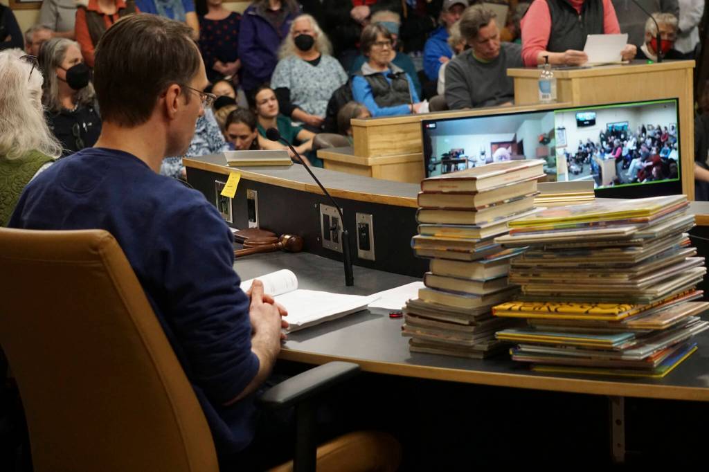 Some of the Homer Public Library books a citizens group has asked be removed from the childrens section lie on a table next to Library Director Dave Berry at the meeting of the Library Advisory Board on Nov. 15, 2022, in the Cowles Council Chambers at Homer City Hall in Homer, Alaska. (Photo by Michael Armstrong/Homer News)