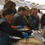 Volunteers from Hilcorp plate food on Friday, Nov. 18, 2022, at the Area-Wide Senior Dinner at Kenai Seniors Center in Kenai, Alaska. (Jake Dye/Peninsula Clarion)