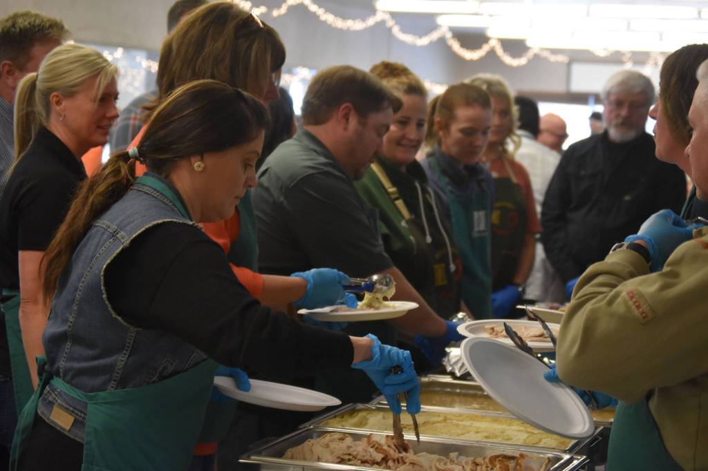 Volunteers from Hilcorp plate food on Friday, Nov. 18, 2022, at the Area-Wide Senior Dinner at Kenai Seniors Center in Kenai, Alaska. (Jake Dye/Peninsula Clarion)