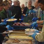 Volunteers from Hilcorp plate food on Friday, Nov. 18, 2022, at the Area-Wide Senior Dinner at Kenai Seniors Center in Kenai, Alaska. (Jake Dye/Peninsula Clarion)