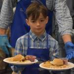 A student from Mountain View Elementary distributes dinners to seniors on Friday, Nov. 18, 2022, at the Area-Wide Senior Dinner at Kenai Seniors Center in Kenai, Alaska. (Jake Dye/Peninsula Clarion)