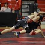 Nikiskis Thayne Quiner leaps into a grab on Kenais Bishop Andruss during a dual meet on Tuesday, Nov. 29, 2022, at Kenai Central High School in Kenai, Alaska. (Jake Dye/Peninsula Clarion)