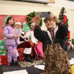 A parent takes a selfie with a child and Santa and Mrs. Claus in Nuiqsut, Alaska, on Nov. 29, 2022. Operation Santa Claus, the Alaska National Guards outreach program, attempts to bring Santa and Mrs. Claus and gifts to children in two or three Alaska Native villages each year, including Nuiqsut in 2022. (AP Photo/Mark Thiessen)