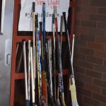 A collection of hockey sticks sit outside in honor of Sam Clyde on Friday, Dec. 16, 2022, at Skyview Middle School in Soldotna, Alaska. (Jake Dye/Peninsula Clarion)