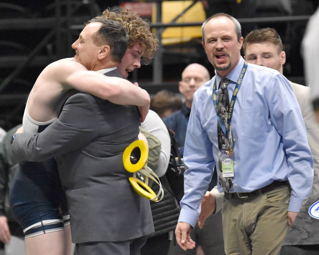Soldotnas Hunter Richardson hugs Stars head coach Neldon Gardner after winning the Division I state title at 189 pounds Saturday, Dec. 18, 2022, at the state wrestling tournament at the Alaska Airlines Center in Anchorage, Alaska. SoHi assistant Pete Dickinson looks on. (Photo by Jeff Helminiak/Peninsula Clarion)