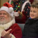 Ken Aaron, in the guise of Santa, smiles for a photo with a group of kids during Breakfast with Santa at the Kenai Senior Center in Kenai, Alaska, on Monday, Dec. 19, 2022. (Jake Dye/Peninsula Clarion)