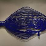 A metal halibut containing a mountain range seen from the Homer Spit, created by Chelline Larsen, hangs Tuesday, Jan. 31, 2023, at the Kenai Art Center, in Kenai, Alaska, as part of Metalwork & Play. (Jake Dye/Peninsula Clarion)