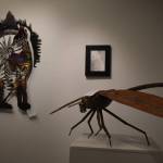 A metal dragonfly sculpted by Dave Emery stands atop a pedestal, two other pieces visible behind it on Tuesday, Jan. 31, 2023, at the Kenai Art Center, in Kenai, Alaska, as part of Metalwork & Play. (Jake Dye/Peninsula Clarion)