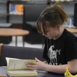 Arianna Imlay searches Girl in the Blue Coat by Monica Hesse for evidence to support a challenge issued during Kenai Peninsula Borough School District Middle School Battle of the Books competition on Thursday, Feb. 9, 2023, at Kenai Middle School in Kenai, Alaska. The challenge would ultimately be declared successful. (Jake Dye/Peninsula Clarion)