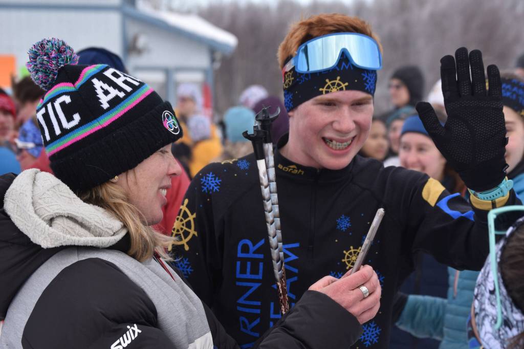 Jody Goodrich reaches out for a high five and smiles alongside Jessie Goodrich, his mother and coach, after he completed the final leg of the boys 4x5-kilometer relay and secured the Homer boys program-first Division II win at the ASAA State Nordic Ski Championships at Kincaid Park in Anchorage, Alaska, on Saturday, Feb. 25, 2023. (Jake Dye/Peninsula Clarion)