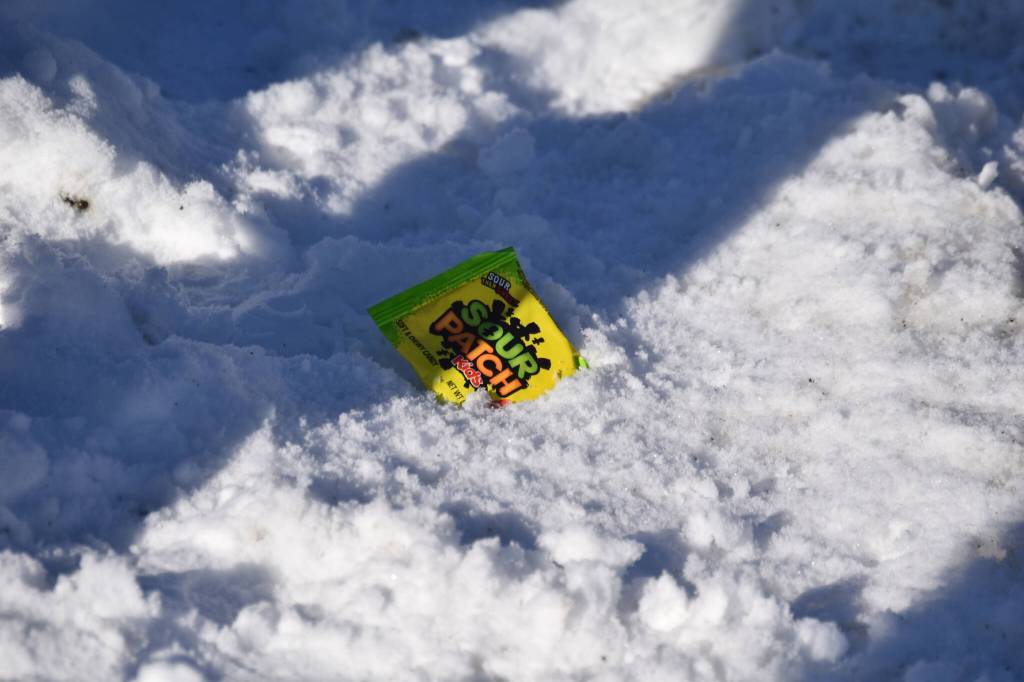 A bag of Sour Patch Kids rest in the snow as the 32nd annual Sweeneys St. Patricks Day Parade proceeds down Fireweed Street in Soldotna, Alaska on Friday, March 17, 2023. (Jake Dye/Peninsula Clarion)