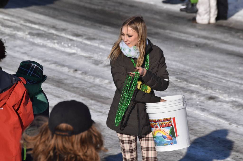 Soldotna Chamber of Commerce Executive Director Maddy McElrea hands out bead necklaces as the 32nd annual Sweeneys St. Patricks Day Parade proceeds down Fireweed Street in Soldotna, Alaska on Friday, March 17, 2023. (Jake Dye/Peninsula Clarion)