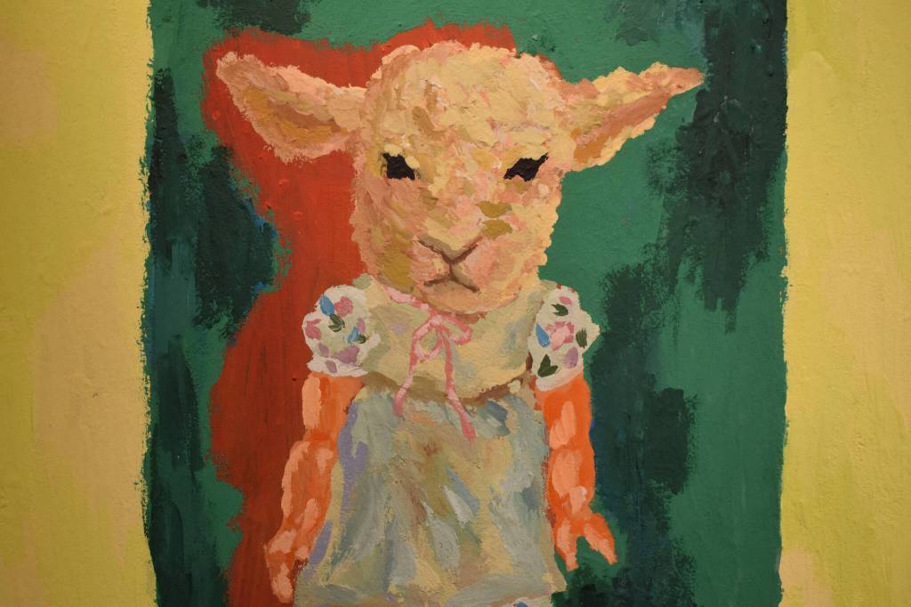 A painting of a child with a sheeps head hangs at the Kenai Art Center in Kenai, Alaska on Wednesday, April 5, 2023, in preparation for the debut of the 32nd Annual Kenai Peninsula Borough School District Visual Feast. (Jake Dye/Peninsula Clarion)