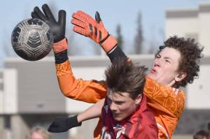 Kodiak goalie Dexter Smith and Kenai Central's Sawyer Vann battle for the ball Thursday, April 20, 2023, at Ed Hollier Field at Kenai Central High School in Kenai, Alaska. (Photo by Jeff Helminiak/Peninsula Clarion)