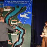 Soldotna High School student Emerson Kapp, second-place winner, is joined on stage by judge Bruce Jackman as she presents the Kenai Peninsula Maze Board during the 33rd Caring for the Kenai competition at Kenai Central High School in Kenai, Alaska on Thursday, April 20, 2023.