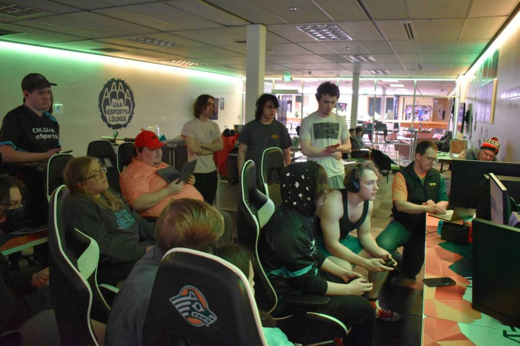 Players, coaches and others gather around while Chugiaks Addison Rains and Kenais Kage Adkins compete during the final match of the Super Smash Bros. Utimate State Championship on Saturday, April 22, 2023 at the University of Alaska Anchorage Esports Lounge in Anchorage, Alaska. (Jake Dye/Peninsula Clarion)