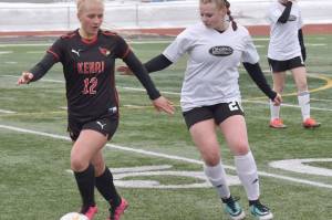 Kenai Central's Kate Wisnewski shields the ball from Nikiski's Wynter Yeager on Tuesday, April 25, 2023, at Ed Hollier Field at Kenai Central High School in Kenai, Alaska. (Photo by Jeff Helminiak/Peninsula Clarion)