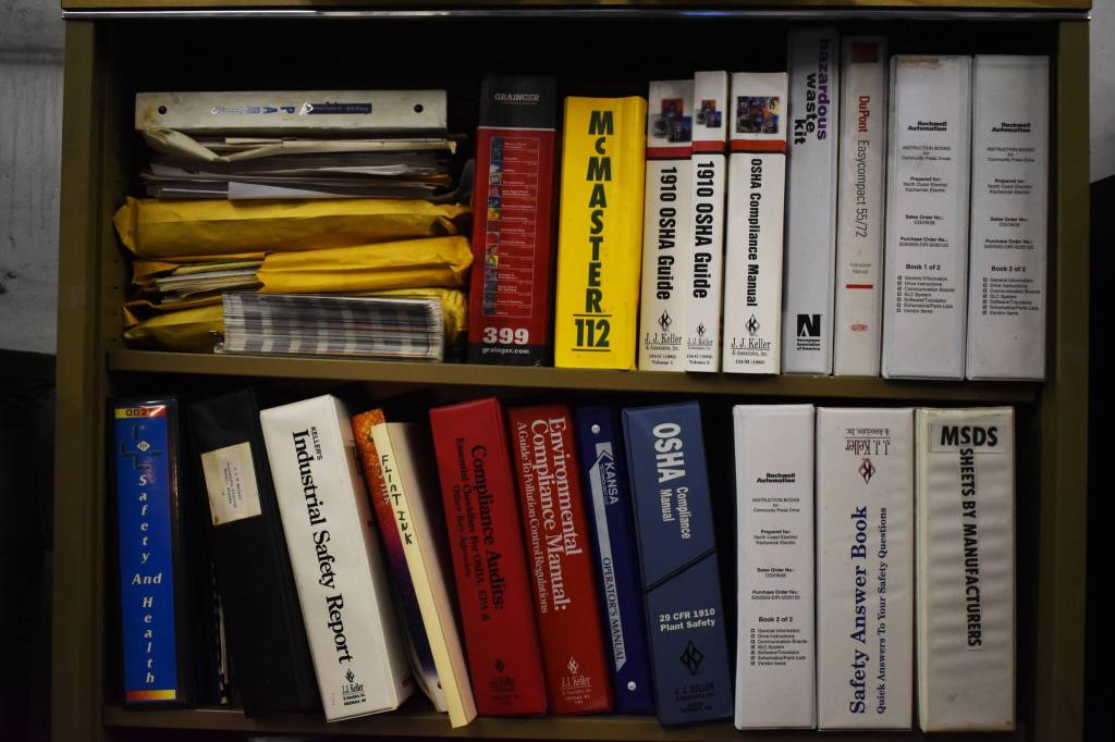 Rows of books and manuals fill a shelf on Monday, April 24, 2023, in the Peninsula Clarion pressroom in Kenai, Alaska. (Jake Dye/Peninsula Clarion)