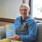 Jake Dye / Peninsula Clarion
Charlie Stephens sits with a copy of his book, Passion Over Pain, on Monday in the Peninsula Clarion offices in Kenai.