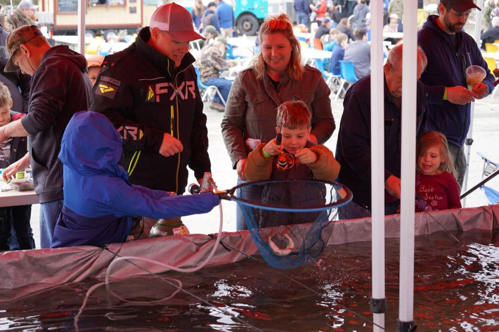 A young boy reels in a rainbow trout while another moves in with a net at the Kenai Peninsula Sport, Rec & Trade Show on Saturday, May 6, 2023, at the Soldotna Regional Sports Complex in Soldotna, Alaska. (Jake Dye/Peninsula Clarion)
