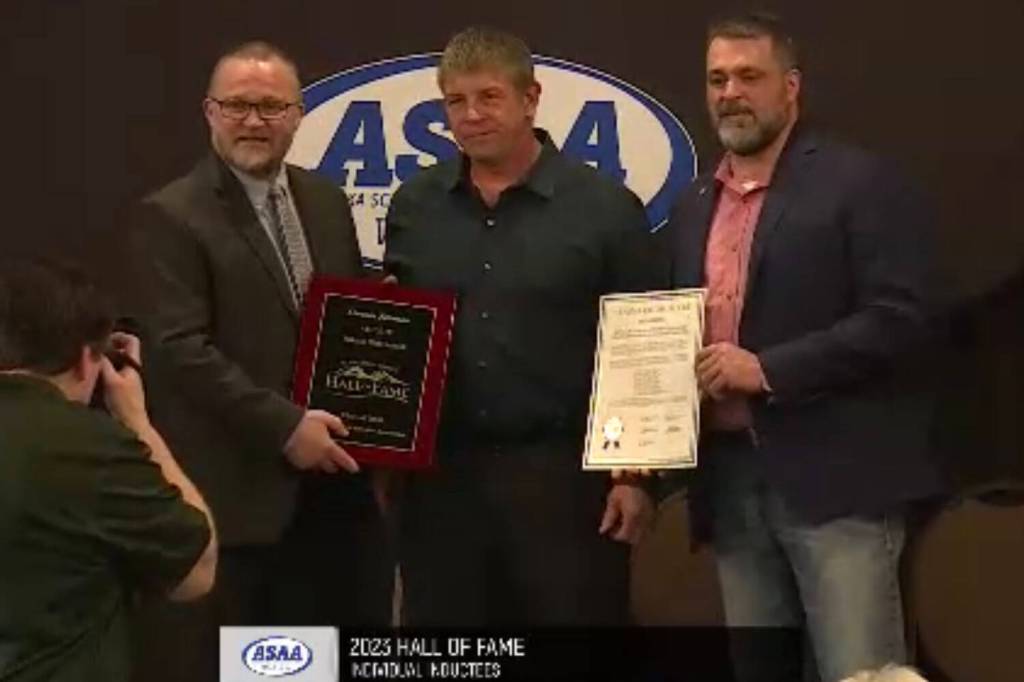 Tim Johnson, center, receives the award for his son Lincoln Johnson at the Alaska High School Hall of Fames Class of 2023 induction ceremony on Sunday, May 7, 2023, at The Lakefront Hotel in Anchorage, Alaska. Lincoln was an inductee of the Class of 2020. (Screenshot)