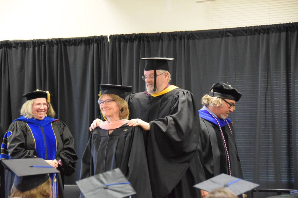 Kachemak Bay Campus Associate Professor of Psychology Brian Partridge (rear center) presents Laura Jean Miller (front center) with her masters hood during the 2023 KBC Commencement on Wednesday, May 10, 2023 in Homer, Alaska. Miller completed her Master of Public Health degree through University of Alaska Anchorage. (Photo by Delcenia Cosman/Homer News)