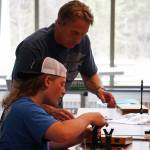 Tony Lewis helps a student with the assembly of a fishing rod during a kids camp put on by Trout Unlimited on Wednesday, May 24, 2023, at the Donald E. Gilman Kenai River Center in Soldotna, Alaska. (Jake Dye/Peninsula Clarion)