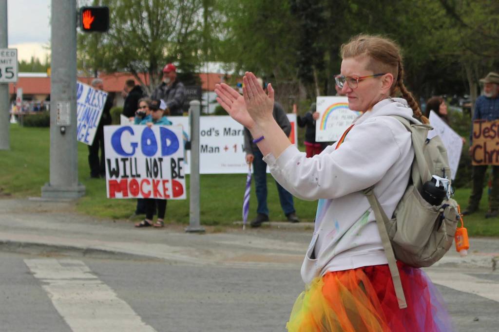Leslie Byrd welcomes marchers to Soldotna Creek Park as part of Soldotna Pride in the Park while protesters stand in the background on Saturday, June 3, 2023 in Soldotna, Alaska. (Ashlyn OHara/Peninsula Clarion)