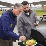 Judges Peter Micciche and Tyler Best sample a salmon dish prepared by chef Lastan Williams of The Catch at Return of the Reds on Saturday, June 3, 2023, at the Kenai City Dock in Kenai, Alaska. (Jake Dye/Peninsula Clarion)