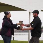 Kenai Chamber of Commerce Executive Director Samantha Springer hands a trophy to Kenai Peninsula Food Bank head chef Stephen Lamm for winning the Return of the Reds Best Salmon Recipe competition on June 3, 2023, at the Kenai City Docks in Kenai, Alaska. (Jake Dye/Peninsula Clarion)