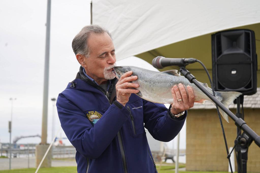 Kenai Peninsula Borough Mayor Peter Micciche kisses the first salmon of the season, caught and auctioned off at Return of the Reds on Saturday, June 3, 2023, at the Kenai City Dock in Kenai, Alaska. (Jake Dye/Peninsula Clarion)