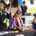 Children try on life jackets during the Kenai River Festival on Friday, June 9, 2023, at Soldotna Creek Park in Soldotna, Alaska. (Jake Dye/Peninsula Clarion)