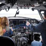 Two attendees sit at the controls inside a large plane displayed at the Kenai Peninsula Air Fair on Saturday, June 10, 2023, at the Kenai Municipal Airport in Kenai, Alaska. (Jake Dye/Peninsula Clarion)