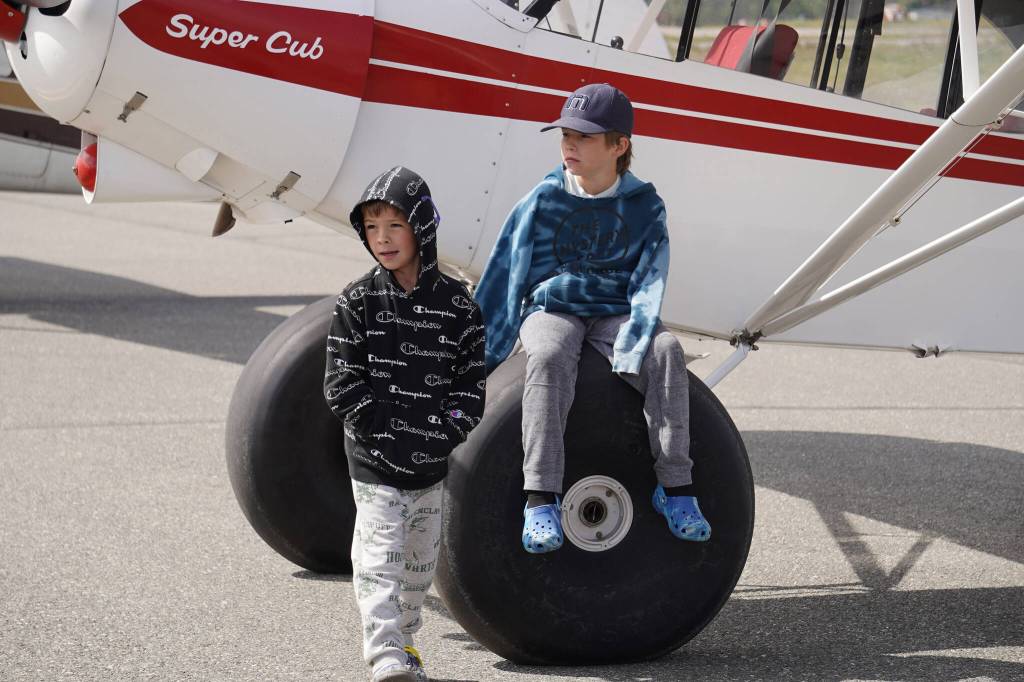 Two kids wait by a plane displayed at the Kenai Peninsula Air Fair on Saturday, June 10, 2023, at the Kenai Municipal Airport in Kenai, Alaska. (Jake Dye/Peninsula Clarion)