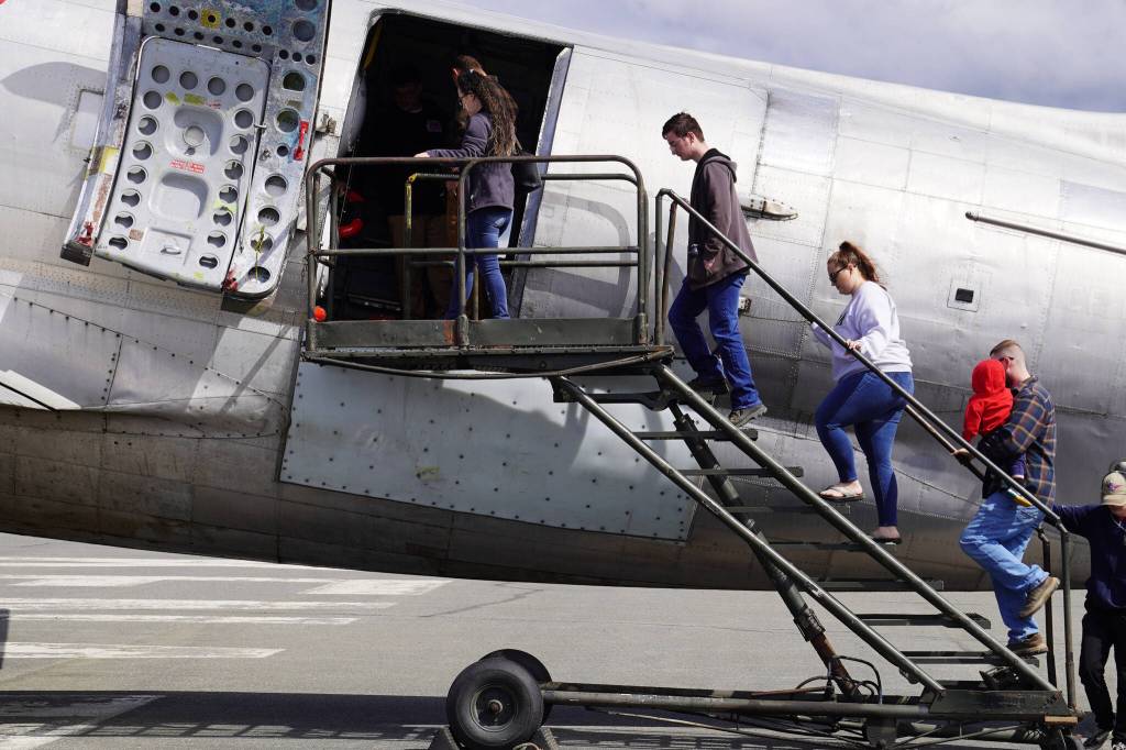 Attendees climb a stairway to tour the inside a large plane displayed at the Kenai Peninsula Air Fair on Saturday, June 10, 2023, at the Kenai Municipal Airport in Kenai, Alaska. (Jake Dye/Peninsula Clarion)
