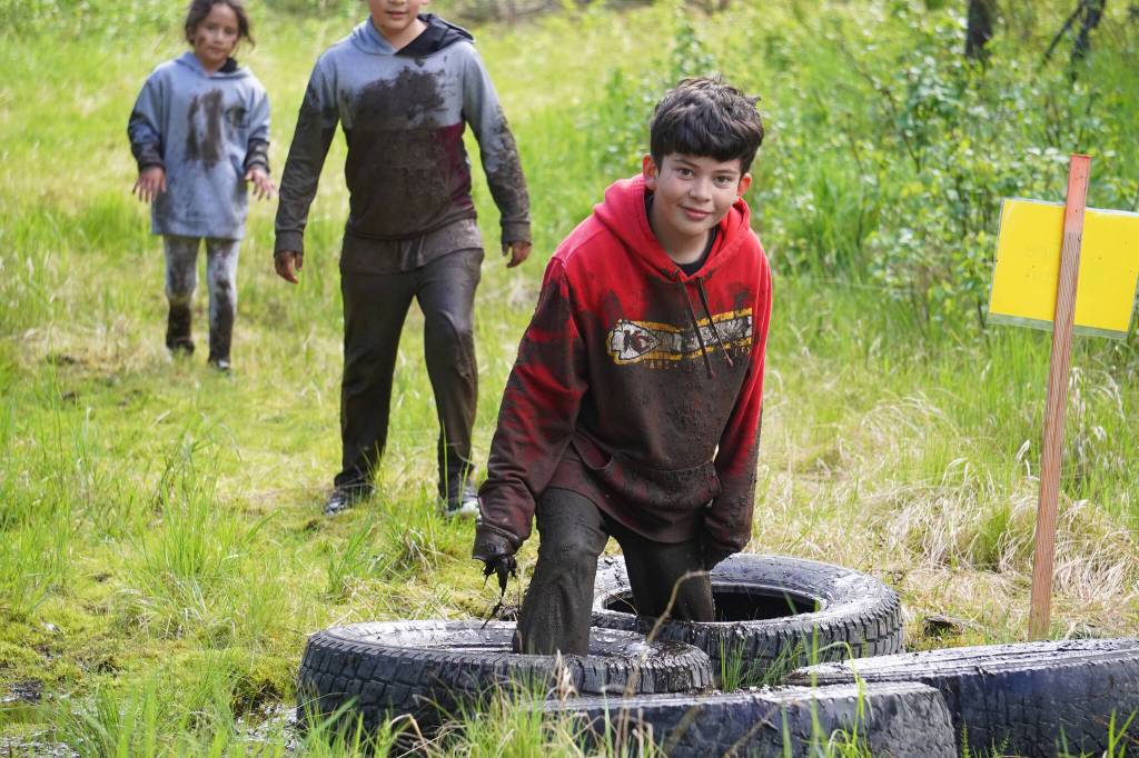 Muddy runners move down the Tsalteshi Trails Porcupine Loop in Soldotna, Alaska, as they participate in the KDLL Mud Run on Friday, June 16, 2023. (Jake Dye/Peninsula Clarion)
