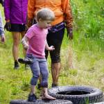 A young contestant balances carefully to avoid falling into the mud during the KDLL Mud Run at Tsalteshi Trails in Soldotna, Alaska, on Friday, June 16, 2023. (Jake Dye/Peninsula Clarion)