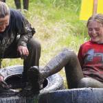 It takes more than one to free a trapped foot during the KDLL Mud Run at Tsalteshi Trails in Soldotna, Alaska, on Friday, June 16, 2023. (Jake Dye/Peninsula Clarion)