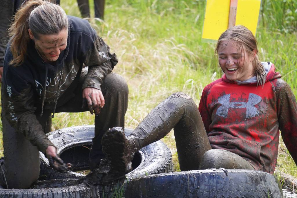 It takes more than one to free a trapped foot during the KDLL Mud Run at Tsalteshi Trails in Soldotna, Alaska, on Friday, June 16, 2023. (Jake Dye/Peninsula Clarion)