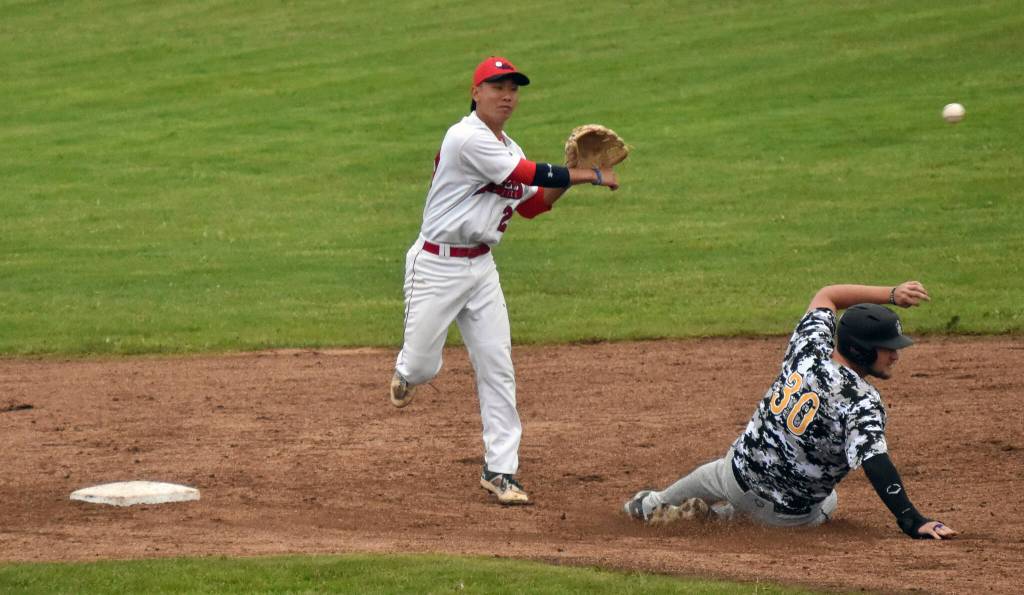 Peninsula Oilers second baseman Ryson Ujimori turns a double play in front of Anchorage Bucs Jaxon Sorenson on Wednesday, June 21, 2023, at Coral Seymour Memorial Park in Kenai, Alaska. (Photo by Jeff Helminiak/Peninsula Clarion)