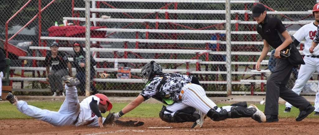 Peninsula Oilers Drewbie Pinkston scores on a sacrifice fly past Anchorage Bucs catcher Trenton Burkhalter to tie the game at 4 in the eighth Friday, June 23, 2023, at Coral Seymour Memorial Park in Kenai, Alaska. (Photo by Jeff Helminiak/Peninsula Clarion)