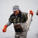 An angler carries a fish from the water at the mouth of the Kasilof River on Monday, June 26, 2023, in Kasilof, Alaska. (Jake Dye/Peninsula Clarion)