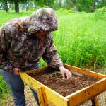 Marcus Wong sifts through a soil sample at an archeological site near Nikiski, Alaska, on Tuesday, June 27, 2023. (Jake Dye/Peninsula Clarion)