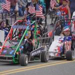 Kids ride carts and wave as the Fourth of July Parade moves down the Kenai Spur Highway in Kenai, Alaska on Tuesday, July 4, 2023. (Jake Dye/Peninsula Clarion)