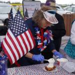 A member of the Kenai Senior Center administers a healthy dollop of cool whip onto a slice of strawberry rhubarb pie during Fourth of July festivities at the softball greenstrip in Kenai, Alaska on Tuesday, July 4, 2023. (Jake Dye/Peninsula Clarion)