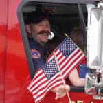 Mitch Miller, of Kenai Fire Department, smiles and waves as the Fourth of July Parade moves down the South Willow Street in Kenai, Alaska on Tuesday, July 4, 2023. (Jake Dye/Peninsula Clarion)