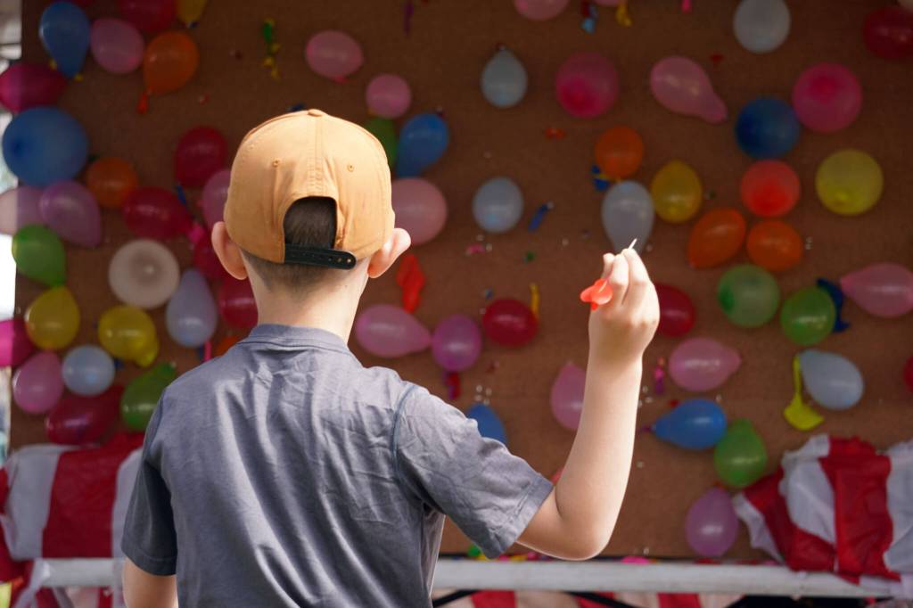 Alex Hamilton readies to throw a dart at the balloon pop, part of the Progress Days Fair at Soldotna Creek Park in Soldotna, Alaska, on Friday, July 21, 2023. (Jake Dye/Peninsula Clarion)