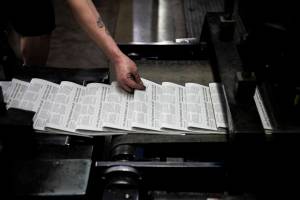 Mike Tullar grabs a Herald to check over as the first papers roll off the press on Wednesday, March 30, 2022 in Everett, Washington. (Olivia Vanni / The Herald)