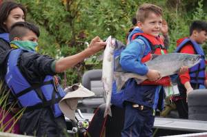 John Gus Knox, right, holds a salmon he caught during the Kenai River Junior Classic in Soldotna, Alaska, on Wednesday, Aug. 9, 2023. (Jake Dye/Peninsula Clarion)